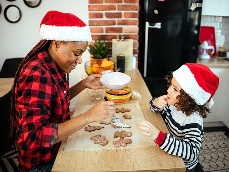 A nanny and young girl doing Christmas cookies together.