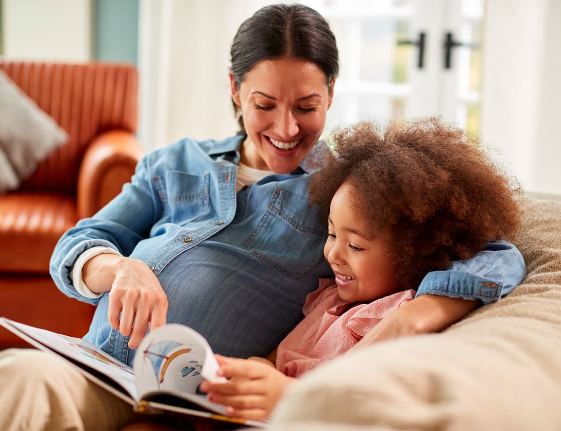 A pregnant mom reading to her daughter.