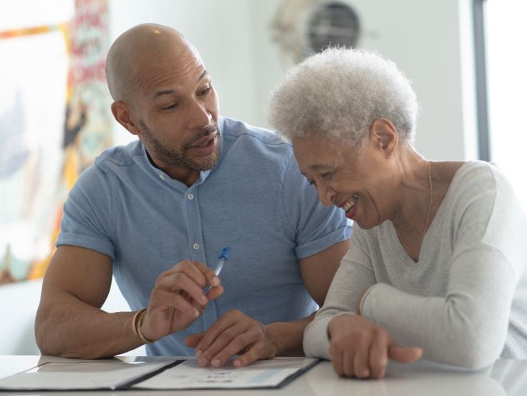 A man talking to an elderly woman, making her smile.