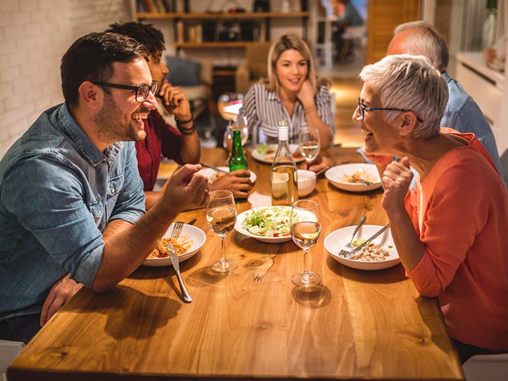 Five adults sitting at a table eating and talking.