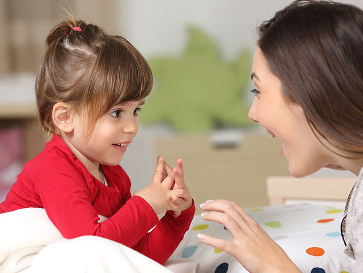 Young girl and caregiver smiling at each other.