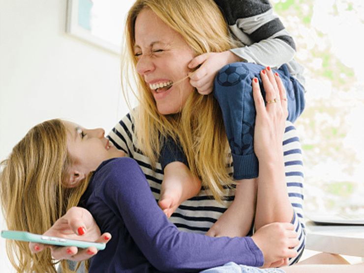 A mom  laughing with her two children.
