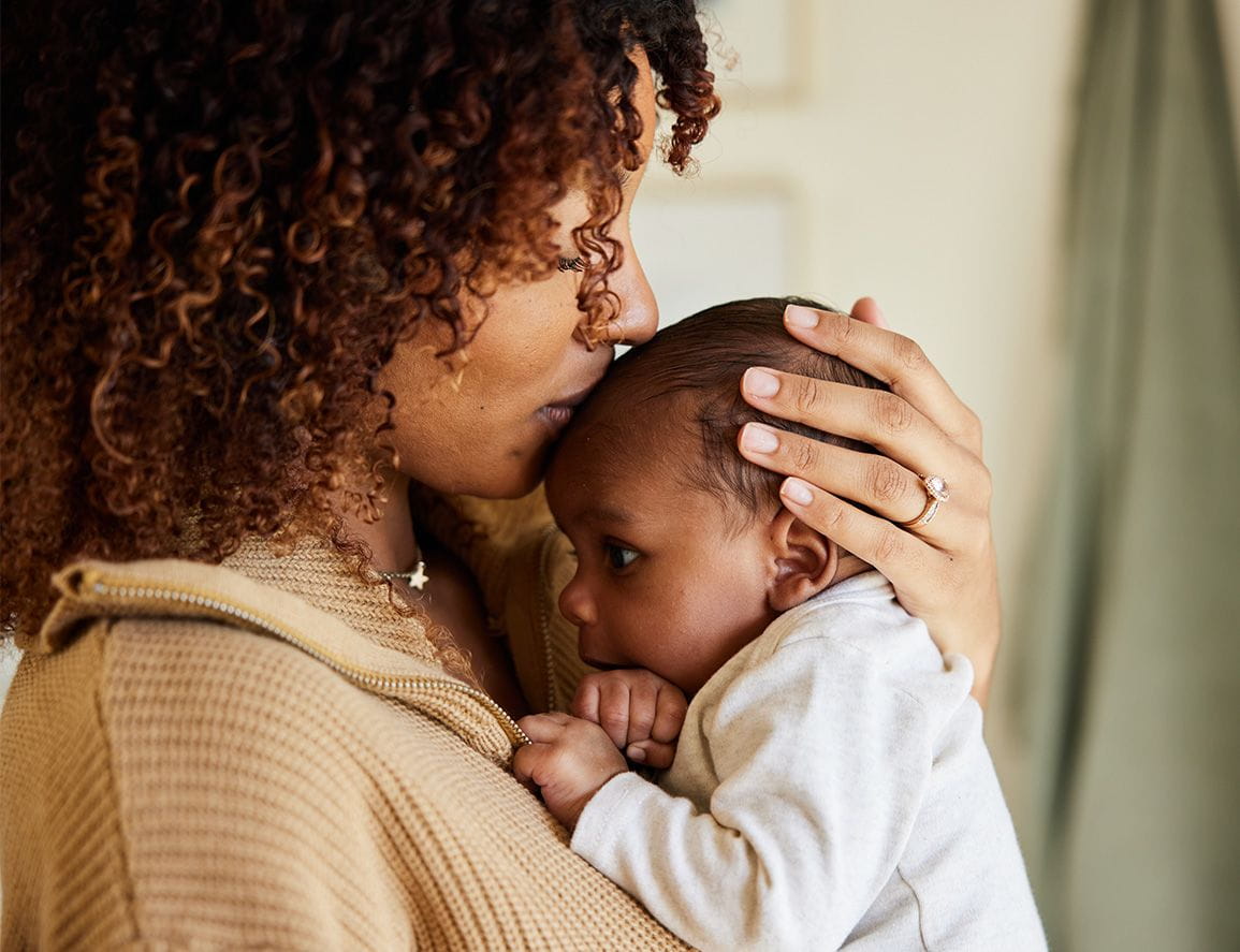 A mom holding her infant in her arms tenderly.
