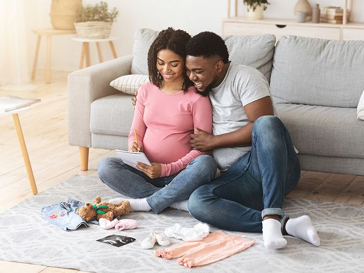 A man and pregnant woman looking at baby items at home as they prepare for their new baby.