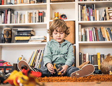 A young boy sitting on the floor holding a toy.