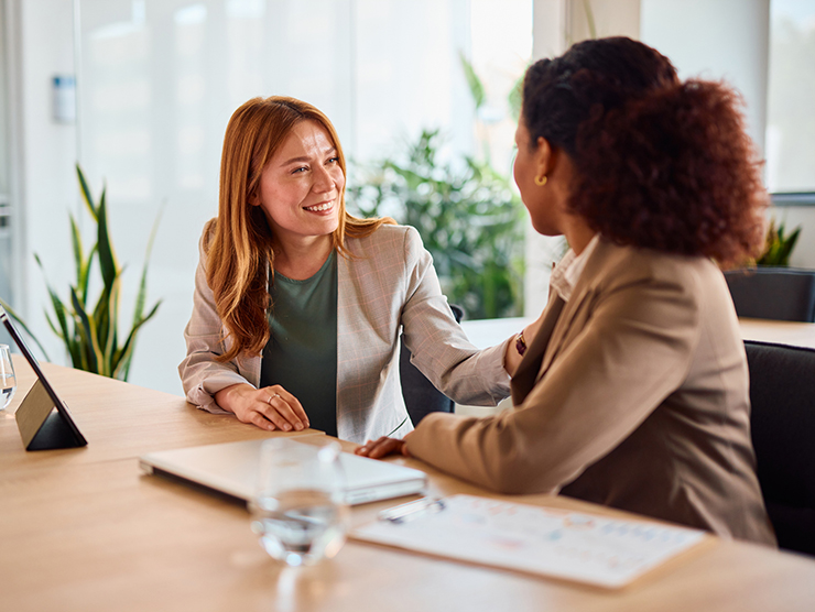 Two adult professionals sitting in an office setting talking to each other