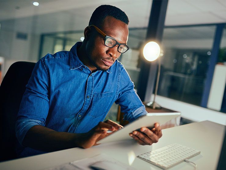 A man sitting at his desk at work with a tablet.