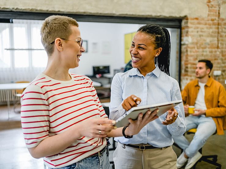 Two workers happily discussing a project in the office.