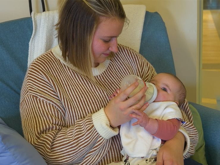 A woman holding a baby while feeding them a bottle