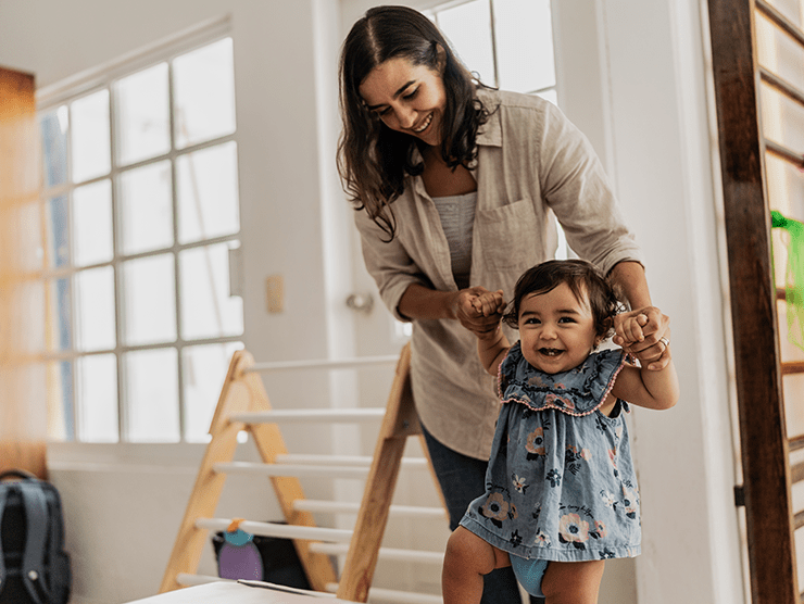 A woman helping a toddler child climb in a classroom setting