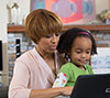 Mom helping her daughter use the computer