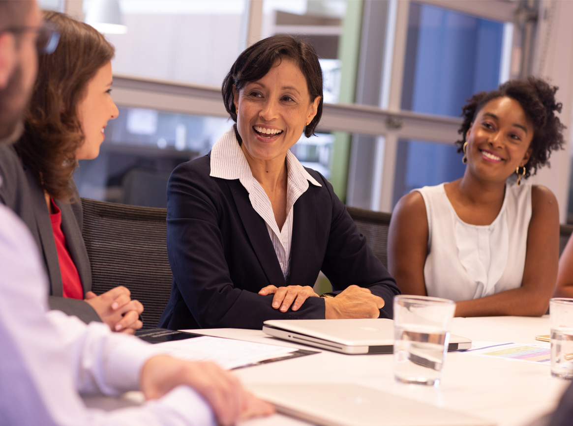 A group of women leaders at a conference table.