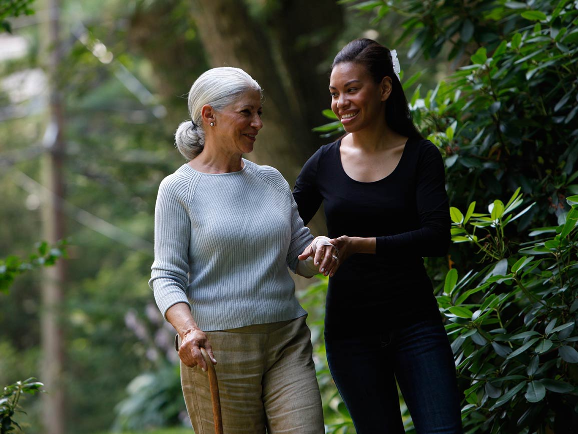 An elderly woman walking with her caregiver