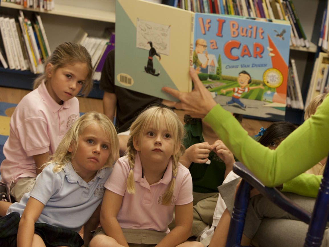 Three toddler girls listening to their teacher reading a story aloud