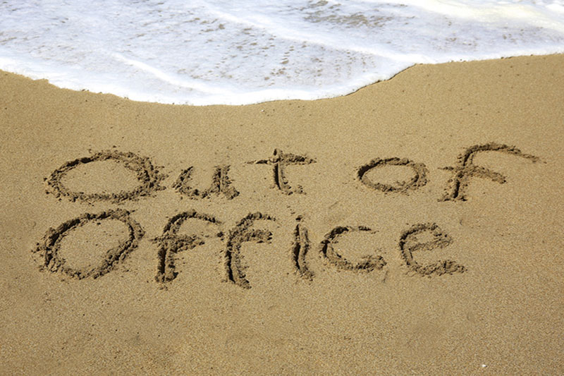"Out of Office" written in the sand