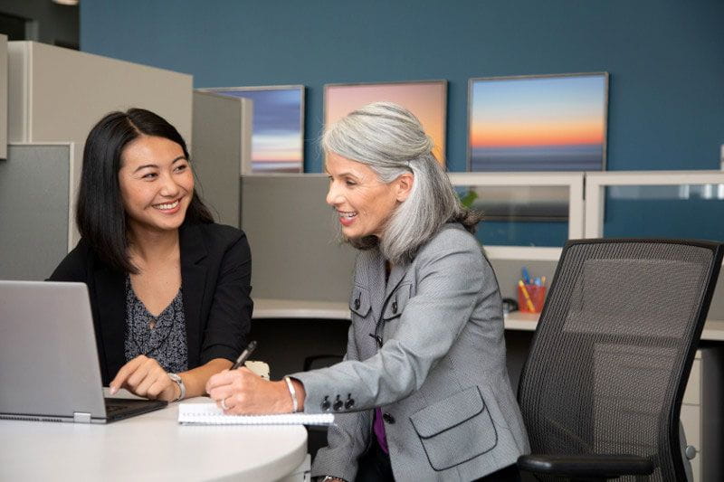 Young employee and her manager looking at benefits on the computer together