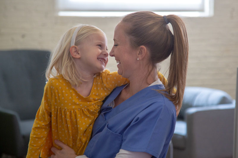 Nurse and working mom hugging her young daughter