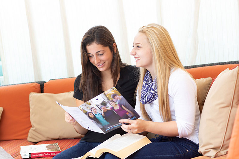 Two high school senior girls researching best value colleges