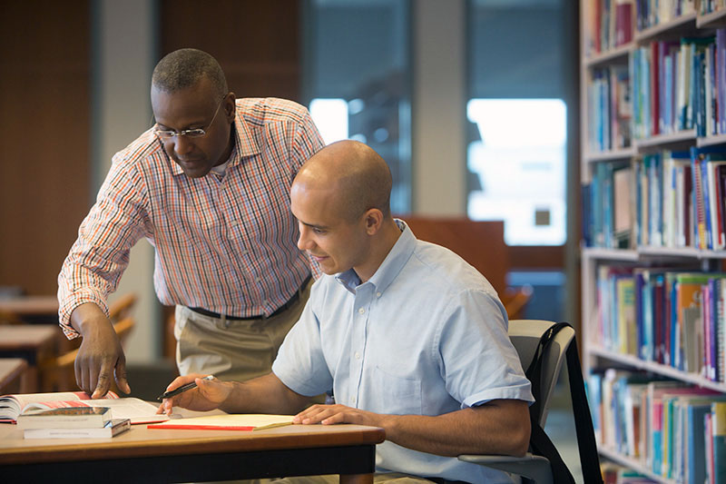 Young man and mentor studying using tuition assistance form his employer