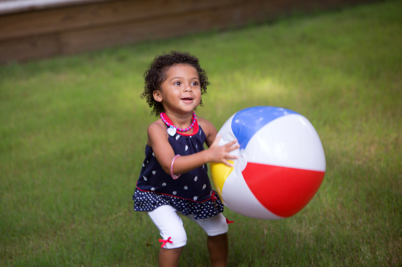 Preschooler playing with a beach ball outside at summer camp