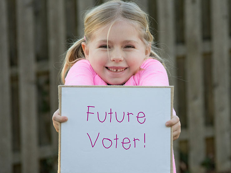 Little girl holding up a sign that says "Future Voter"