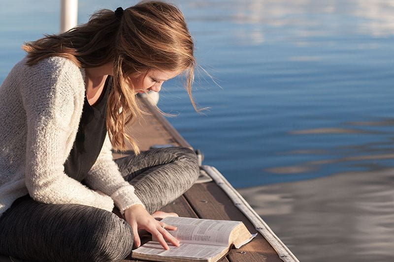 Young female adult learner studying on a dock during summer