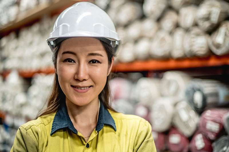 Female manufacturing employee in a hard hat in the warehouse