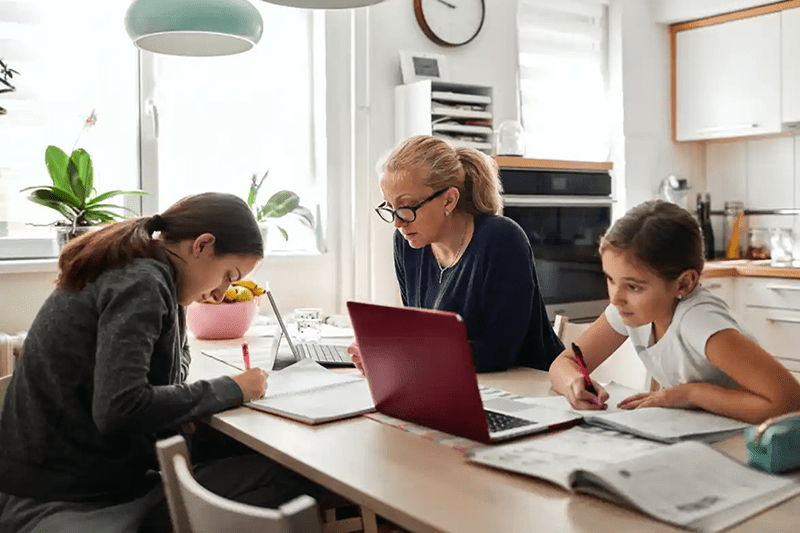 Mom working from home while helping her children with homework