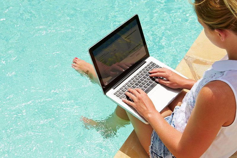 Employee working on her computer at the pool on vacation