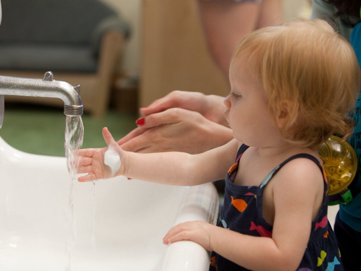 Toddler girl washing her hands at a sink