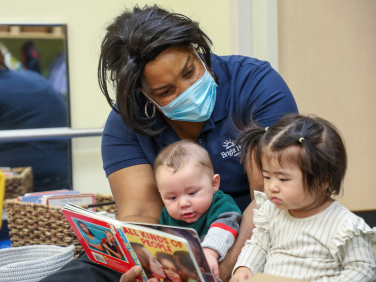 teacher with mask on reading to babies