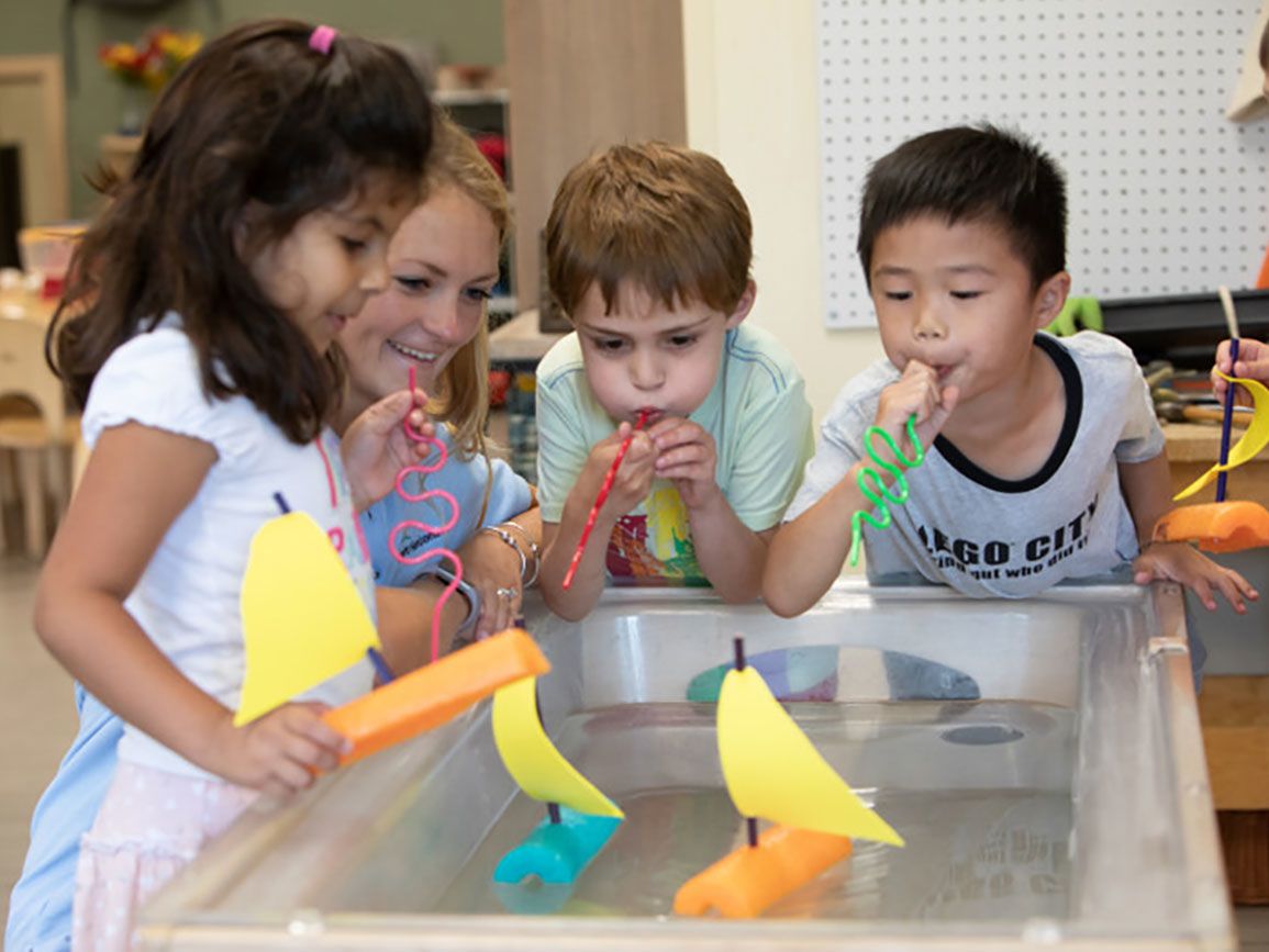 Young kids testing physics principle of buoyancy using paper boats in water