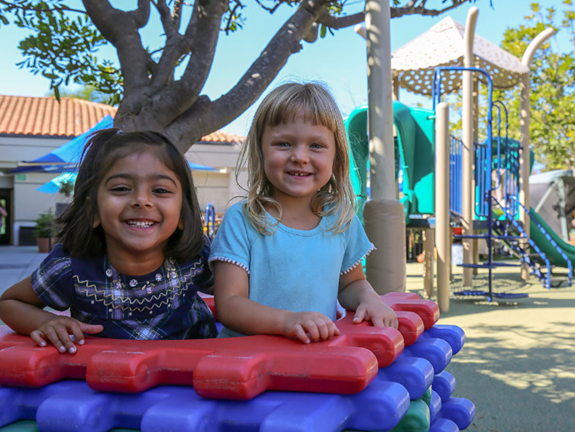 Two preschool girls playing together on the playground