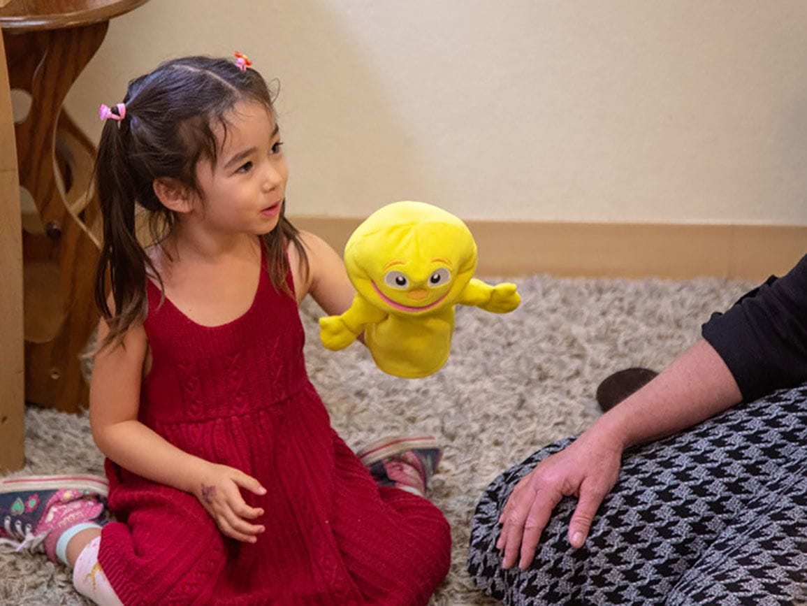Young girl learning empathy through play with puppets