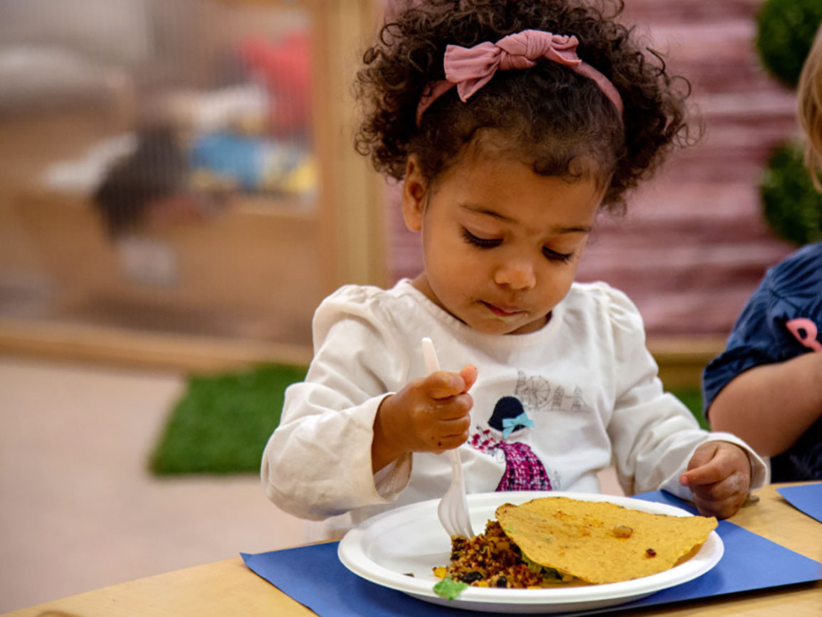 Preschool girl eating a healthy meal at a child care center