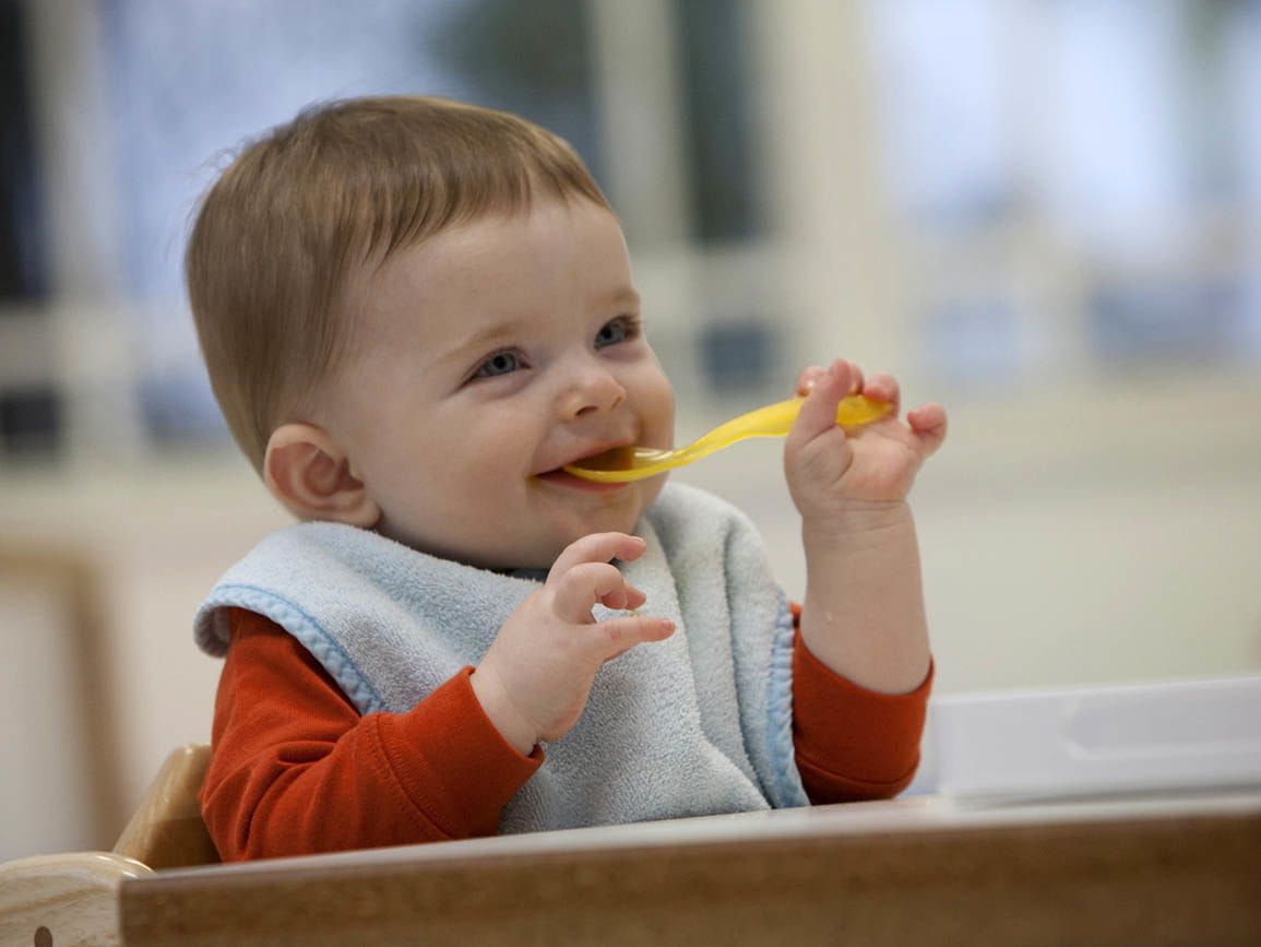 An infant eating with a spoon