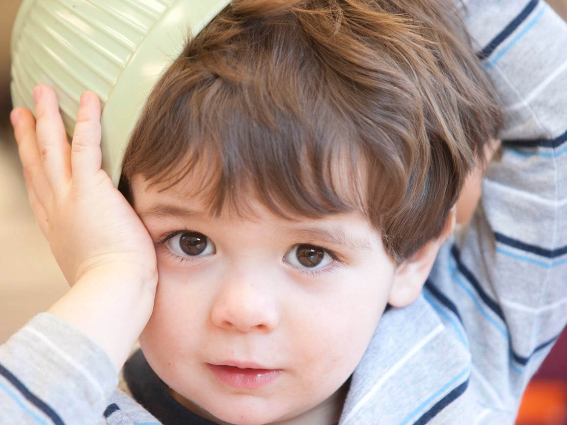 A toddler with a bowl on his head