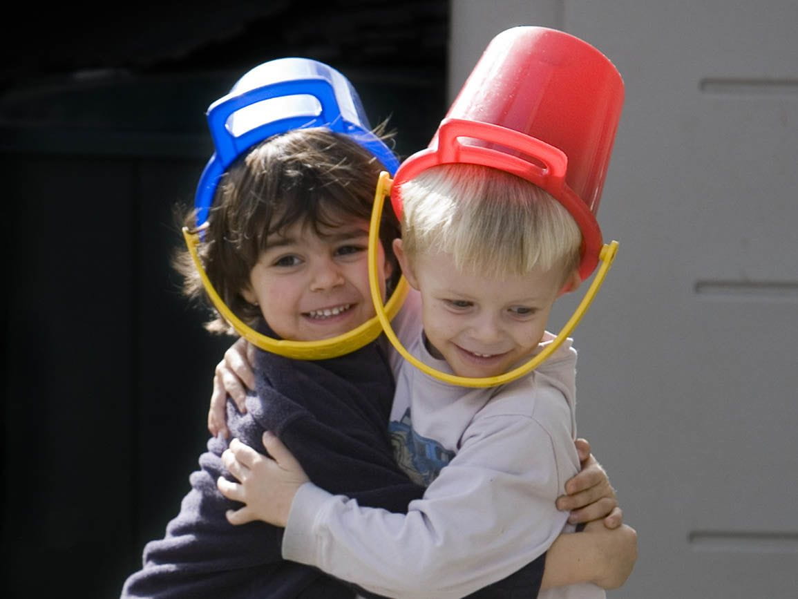 Two friends playing with buckets on their heads