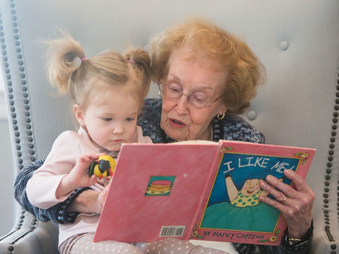 Grandmother reading to her toddler granddaughter