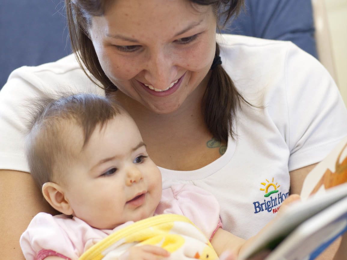 A Bright Horizons child care teacher reading to a baby