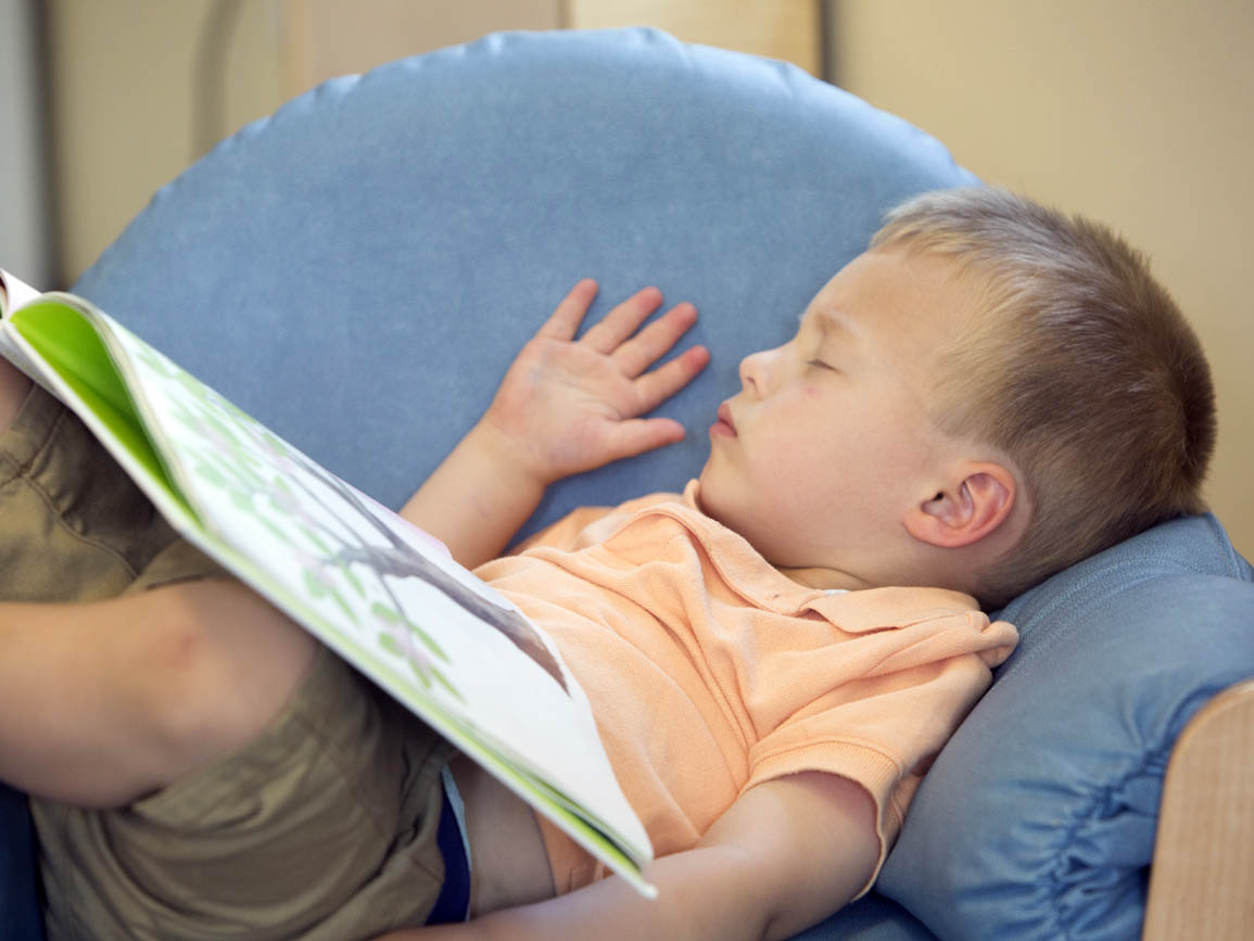 A child napping with a book on his lap