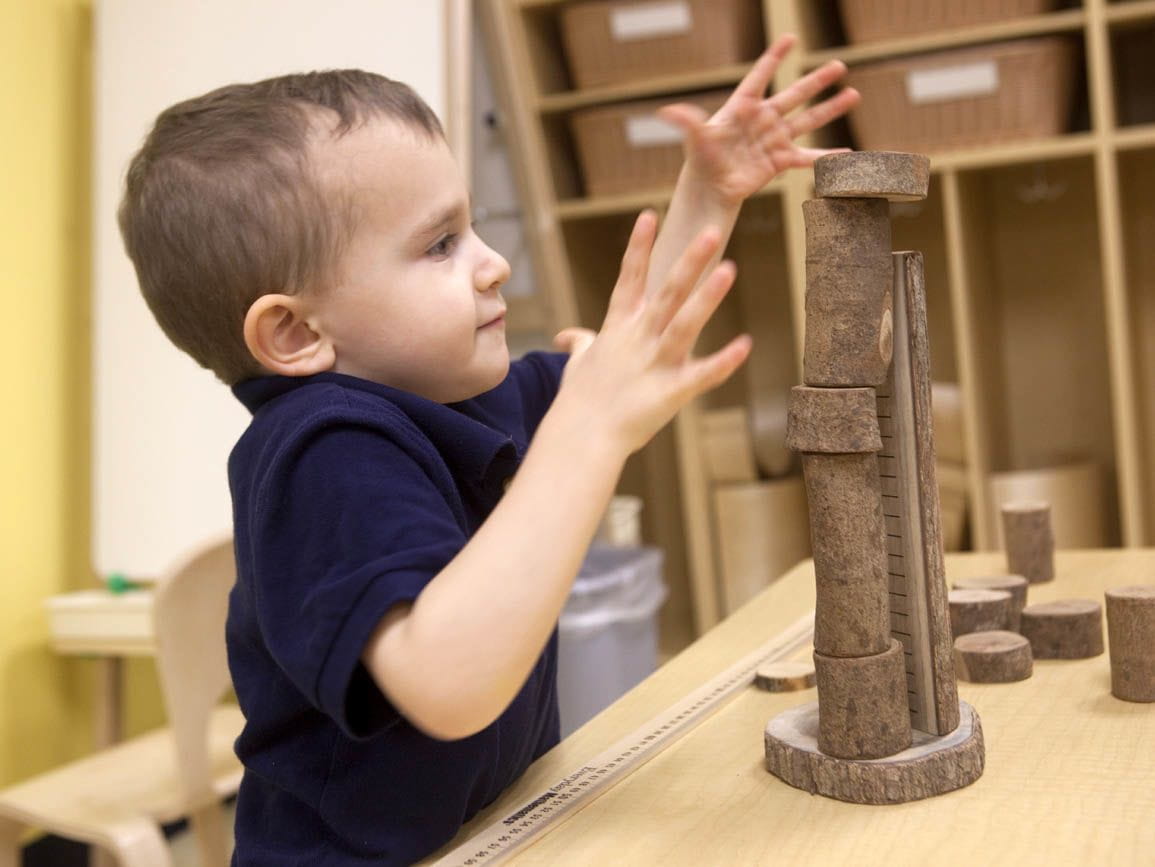Preschool boy building a tower of wooden blocks
