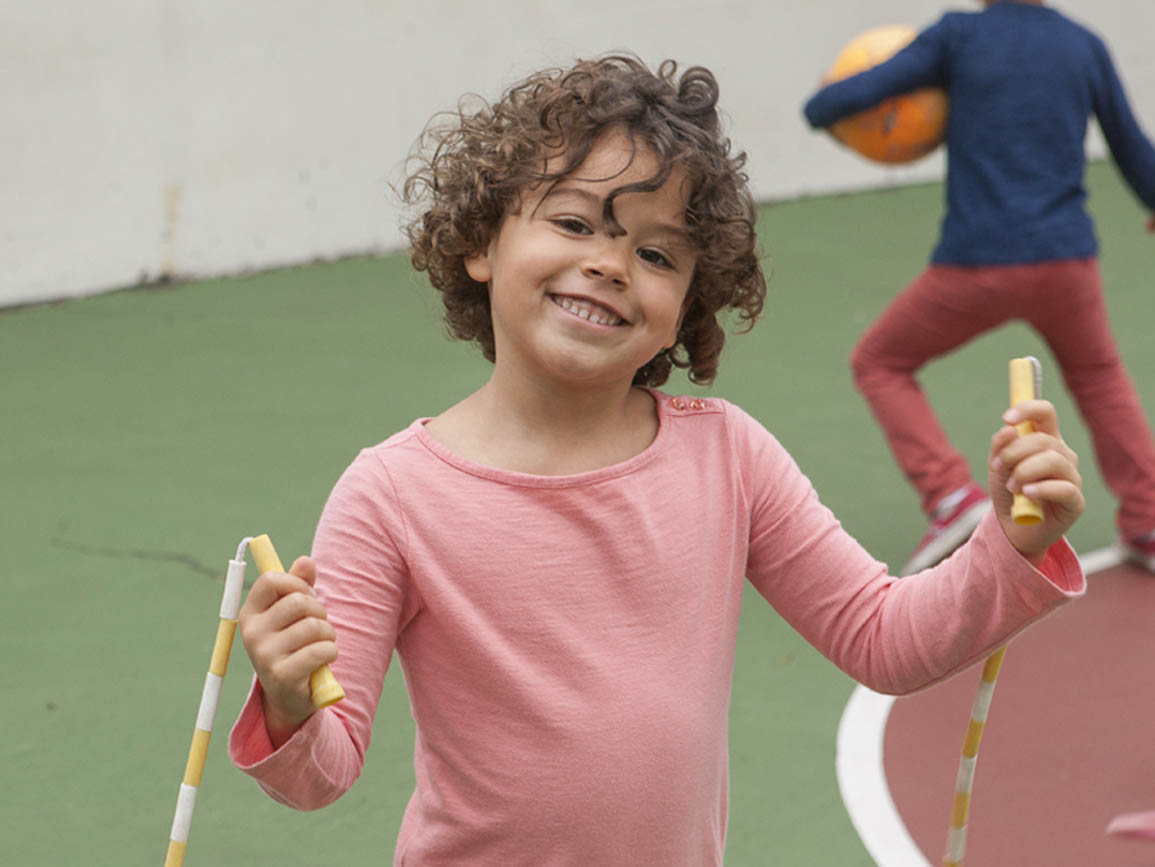 Kindergarten-aged girl using a jump rope at the playground