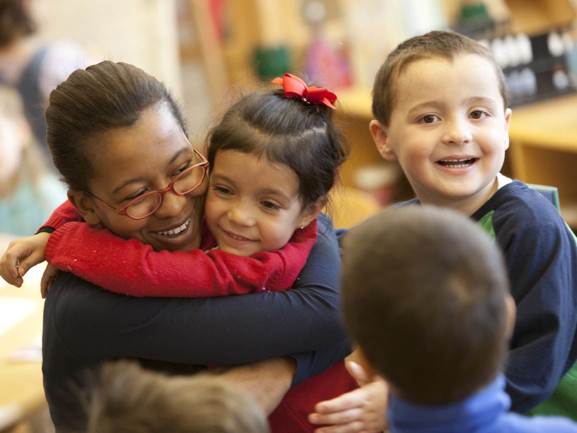 Pre-kindergarten kids hugging teacher goodbye