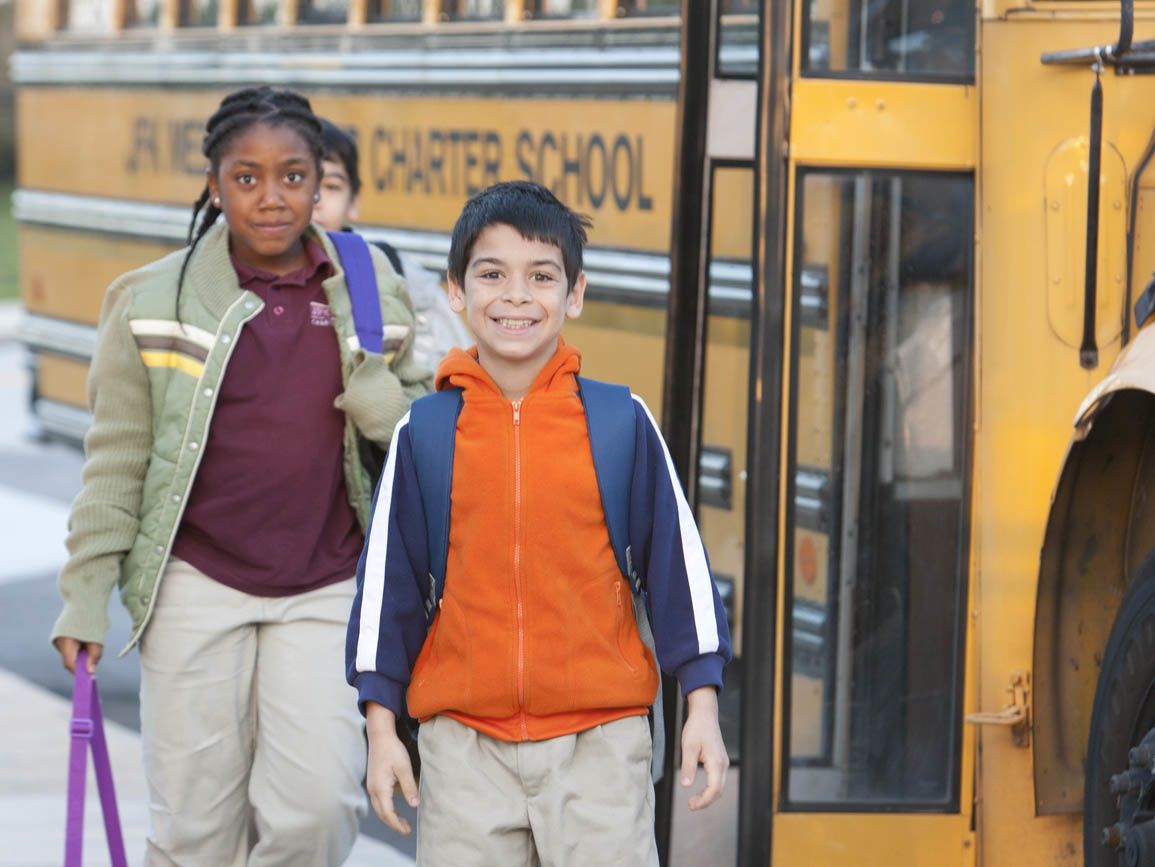 Elementary school-aged boy and girl at school bus