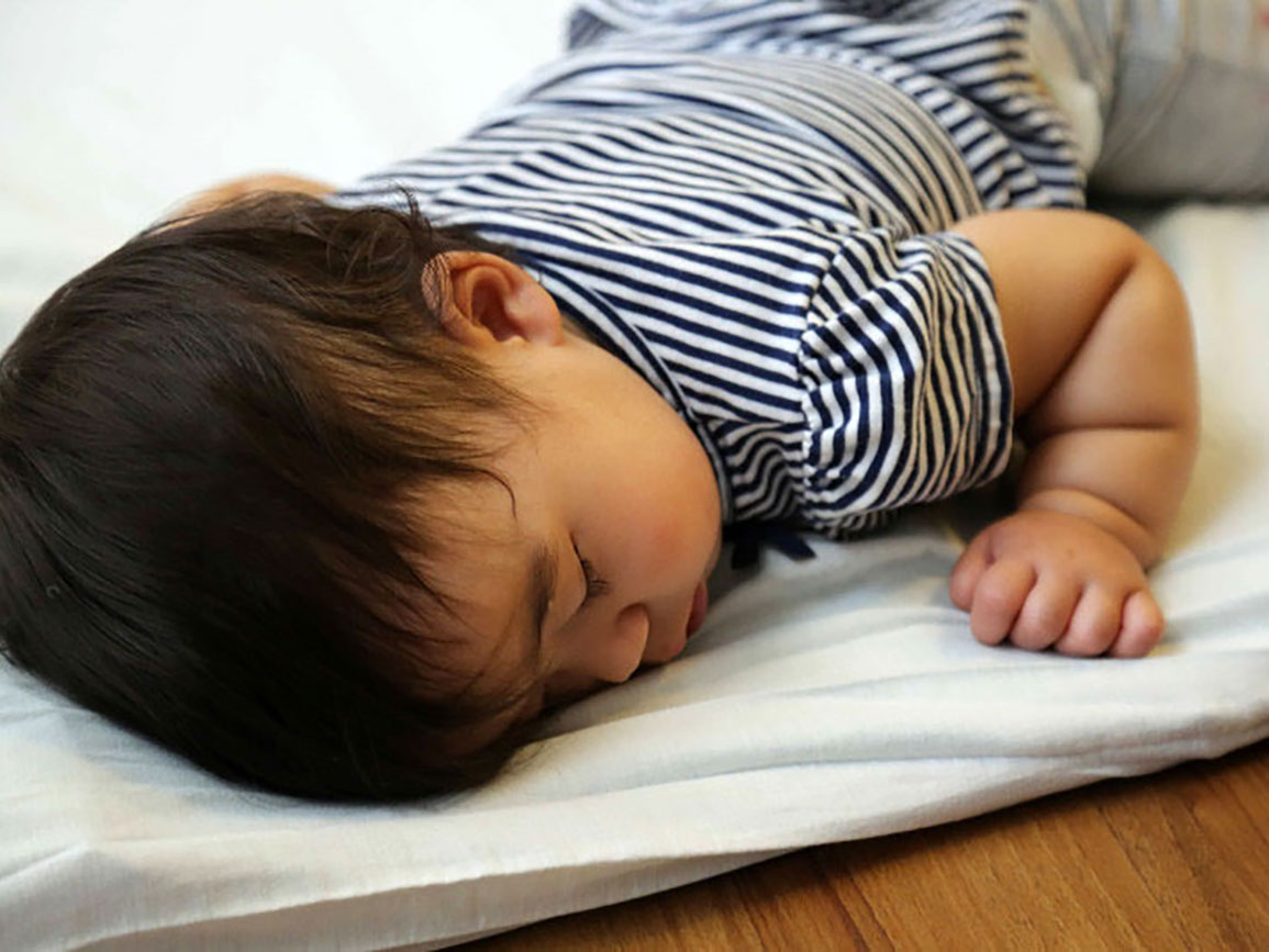 Toddler boy napping on a pad