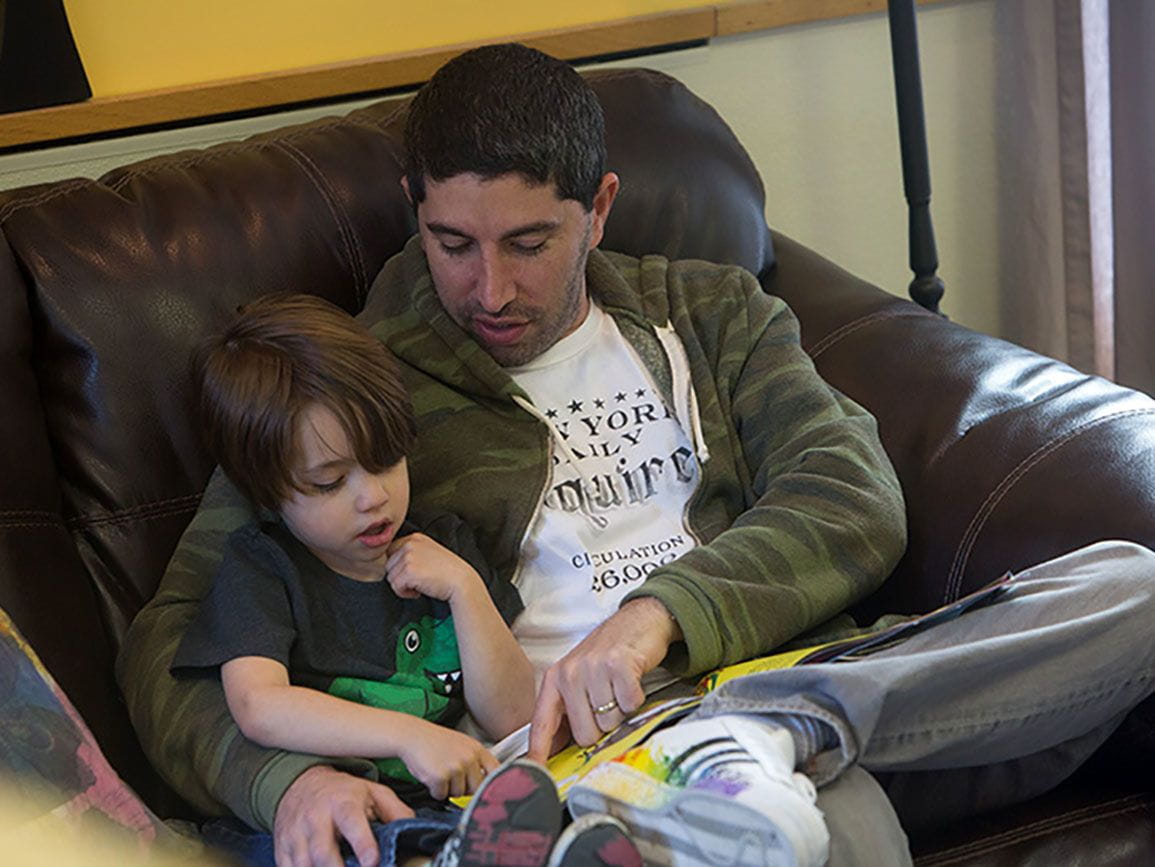 Father reading to his young son on a couch