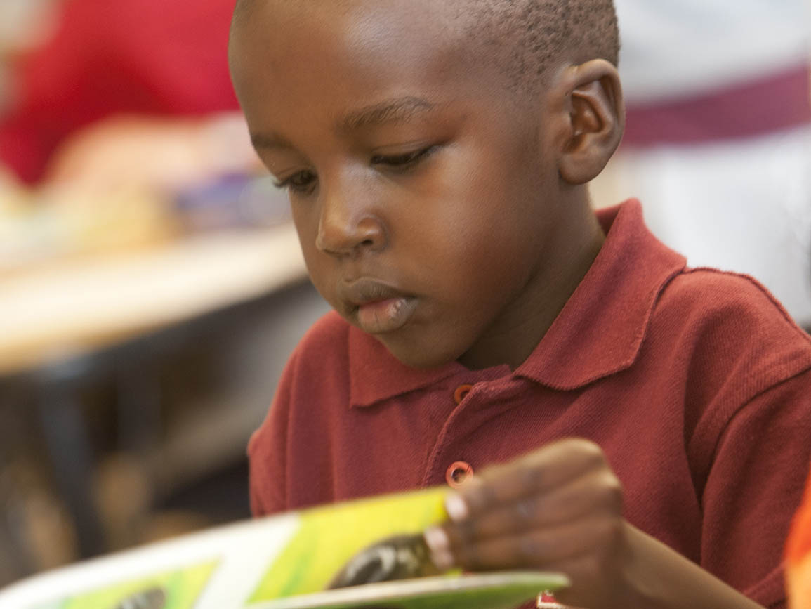 Pre-kindergarten boy sitting and reading a book