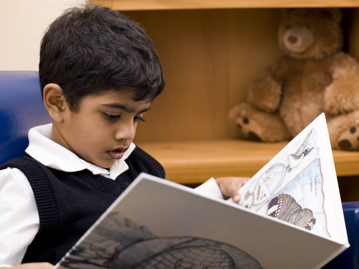 Preschool aged boy sitting and reading a book