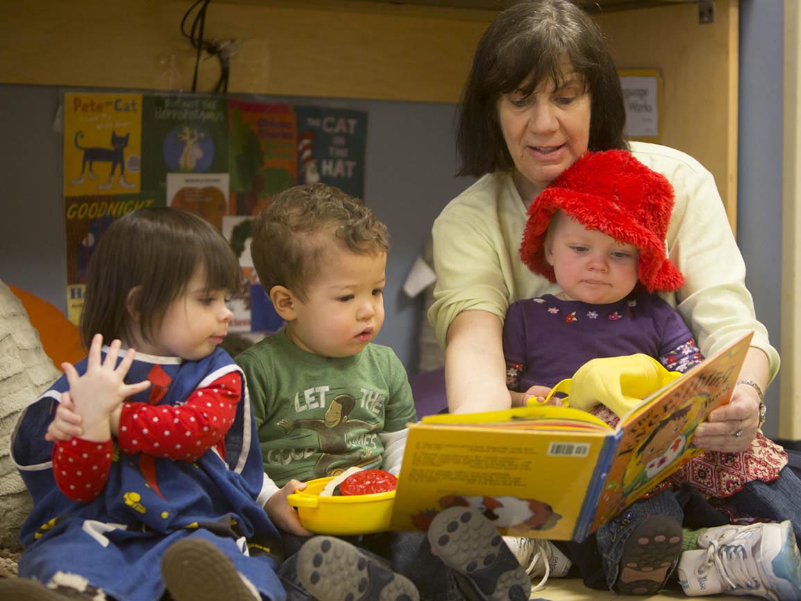 Teacher reading to three toddlers